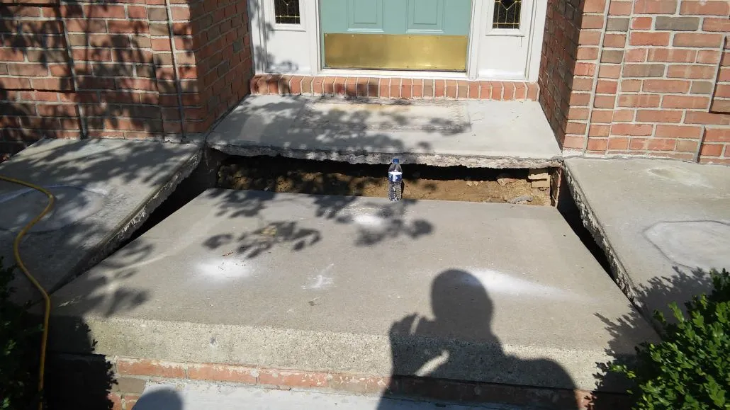 Concrete steps with a hole showing underlying soil