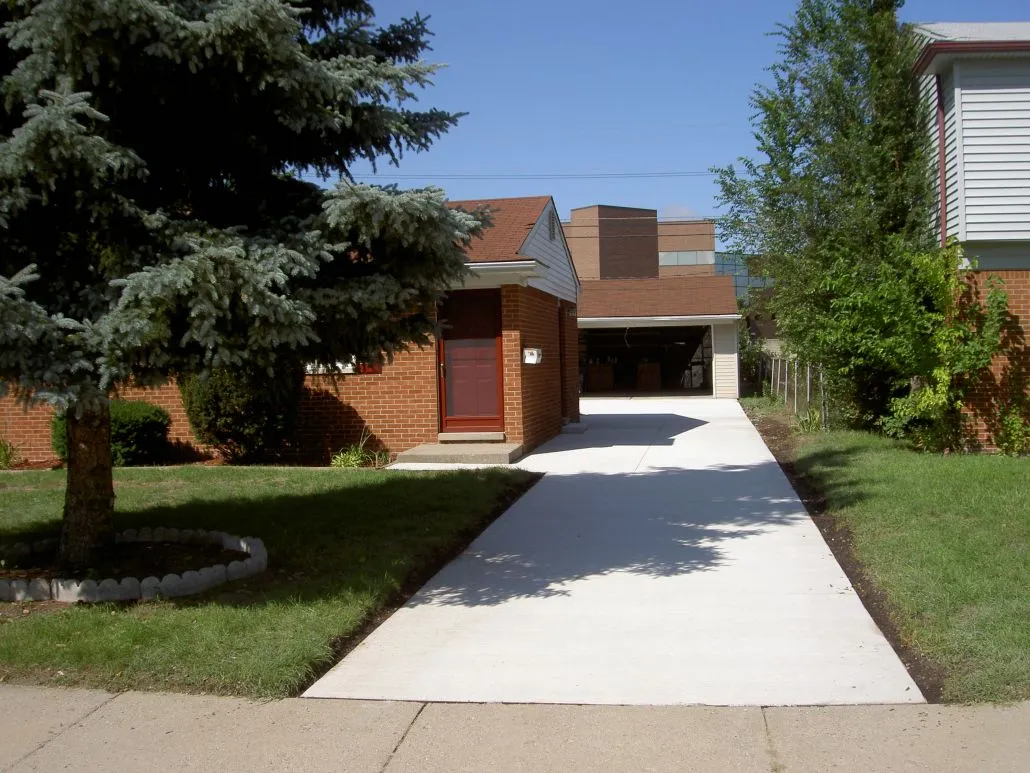 Residential driveway leading to a home with greenery and blue sky