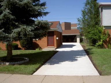 Residential driveway leading to a home with greenery and blue sky