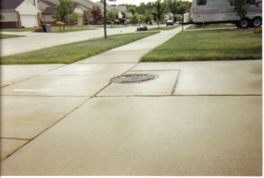 Residential street with concrete sidewalk and manhole cover